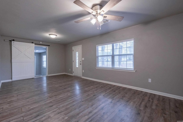 interior space featuring dark wood-style floors, plenty of natural light, baseboards, and a barn door