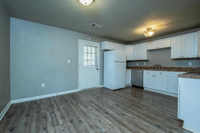 kitchen featuring visible vents, dark countertops, dark wood-style floors, freestanding refrigerator, and dishwasher