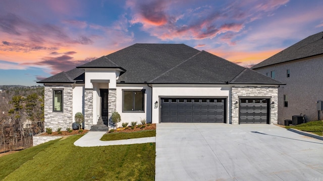 view of front of property with a lawn, stone siding, concrete driveway, a shingled roof, and a garage