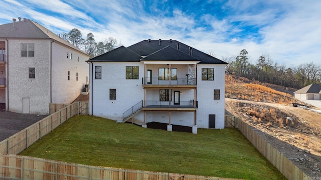 back of house featuring a balcony, a fenced backyard, and a lawn