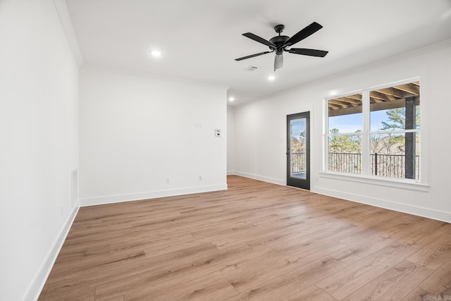 unfurnished room with light wood finished floors, visible vents, crown molding, and baseboards