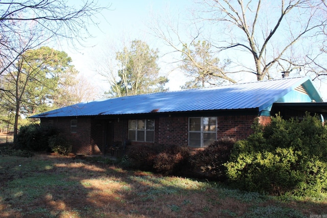 exterior space featuring brick siding and metal roof