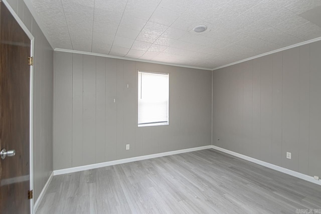 empty room featuring baseboards, wood finished floors, and crown molding