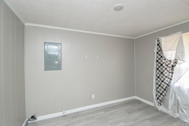 spare room with electric panel, baseboards, wood finished floors, and crown molding