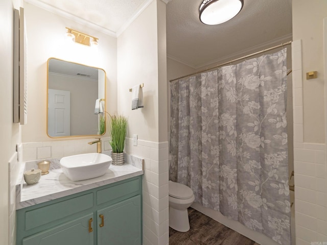 bathroom featuring a textured ceiling, wood finished floors, tile walls, crown molding, and vanity
