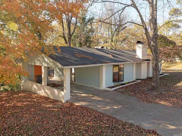 exterior space featuring brick siding, a chimney, and a shingled roof