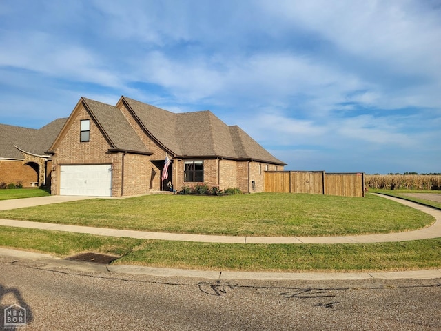 view of front facade with driveway, a front lawn, fence, a shingled roof, and brick siding