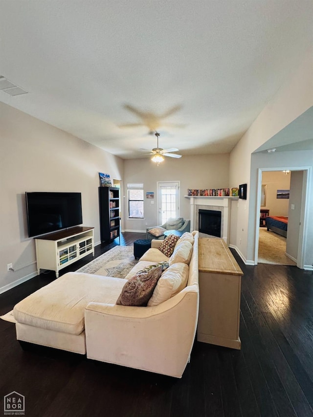 living area featuring visible vents, ceiling fan, baseboards, dark wood finished floors, and a fireplace