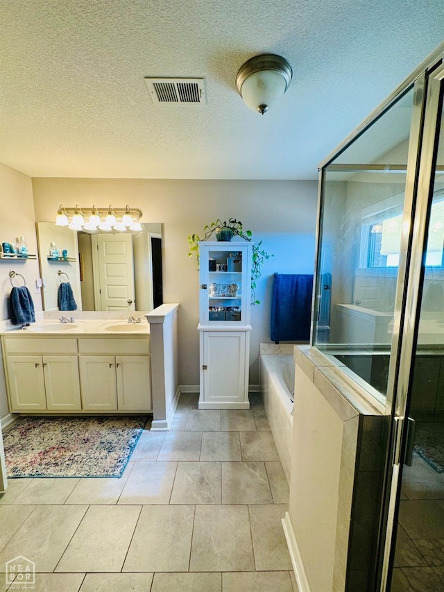 full bathroom with visible vents, a garden tub, double vanity, a stall shower, and a sink