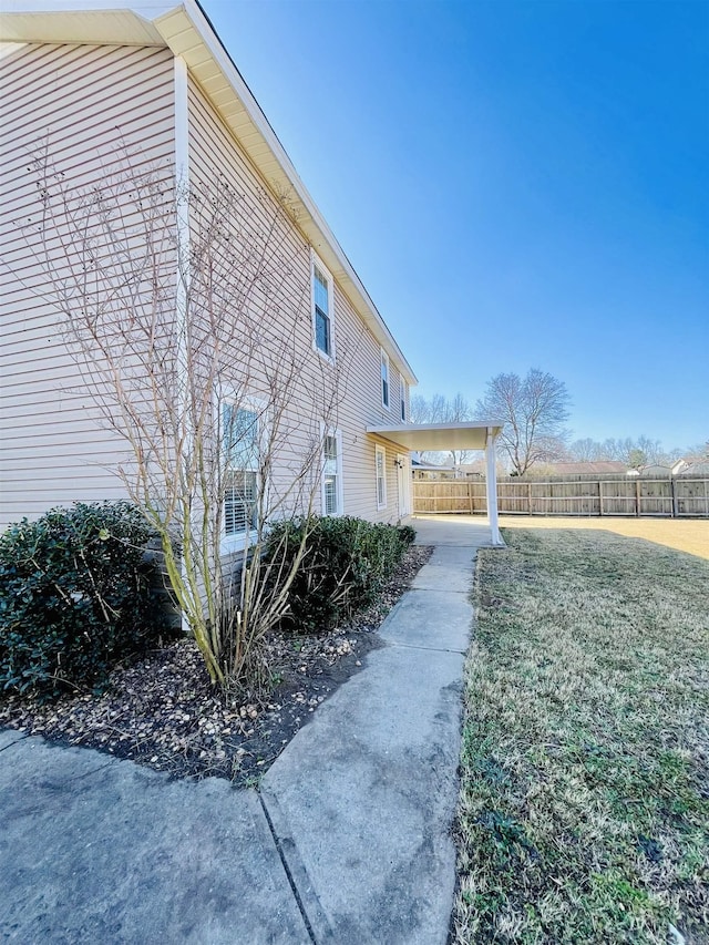 view of property exterior with a lawn and fence