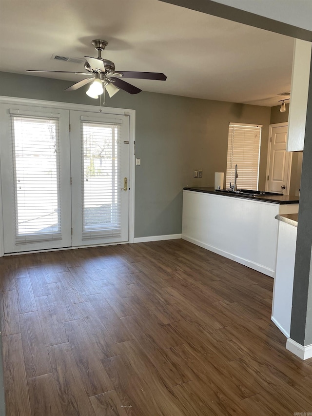 interior space with visible vents, baseboards, dark wood-style floors, and a ceiling fan