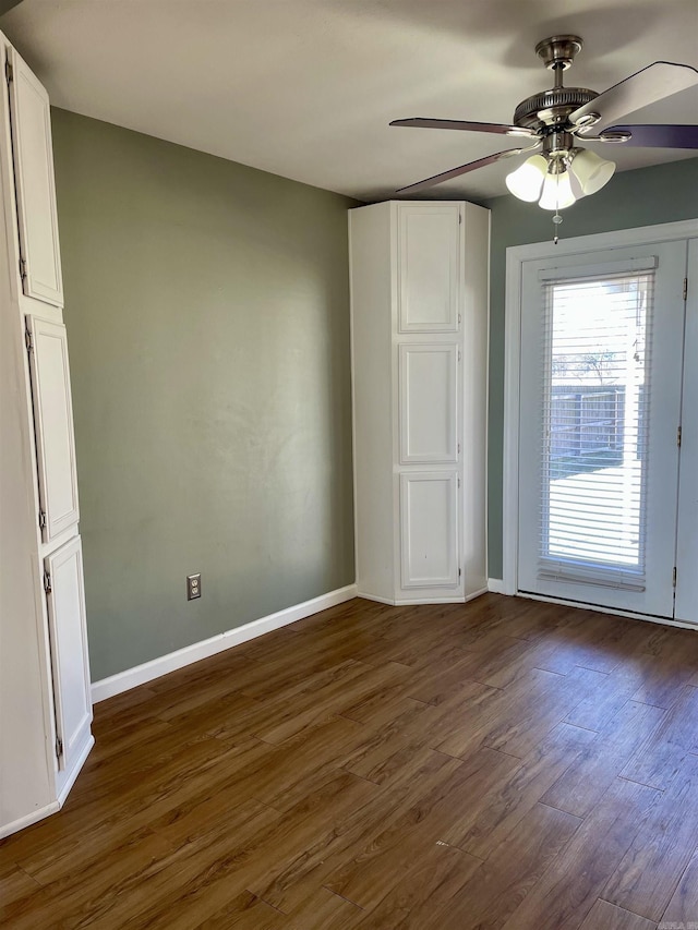 unfurnished bedroom featuring baseboards, dark wood-style floors, and a ceiling fan