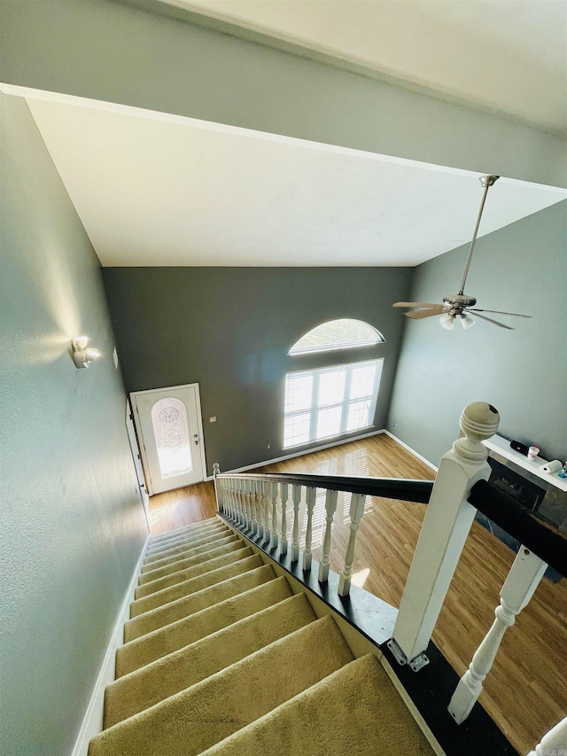 stairs featuring baseboards, lofted ceiling, and wood finished floors