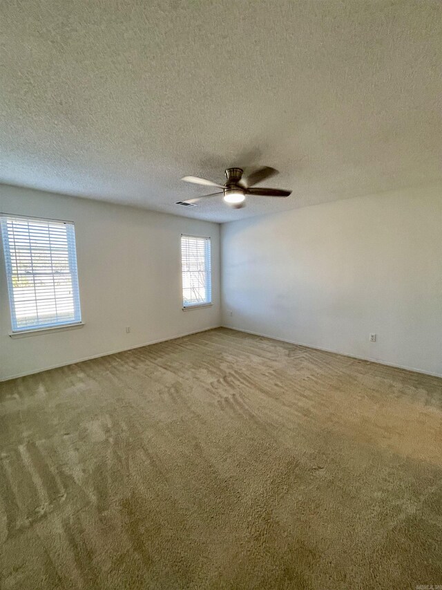 carpeted spare room featuring a textured ceiling and ceiling fan