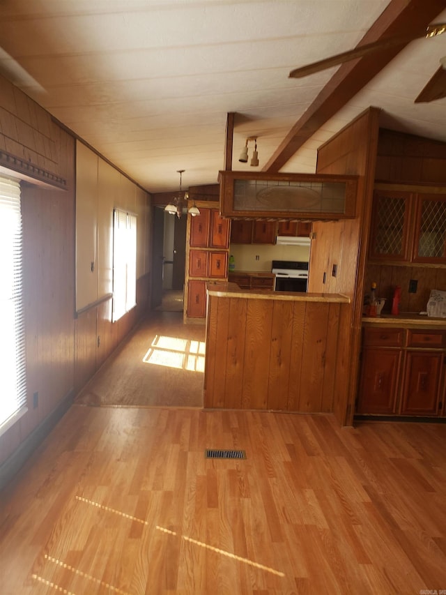 kitchen featuring a peninsula, light wood-style flooring, a chandelier, and range with electric cooktop