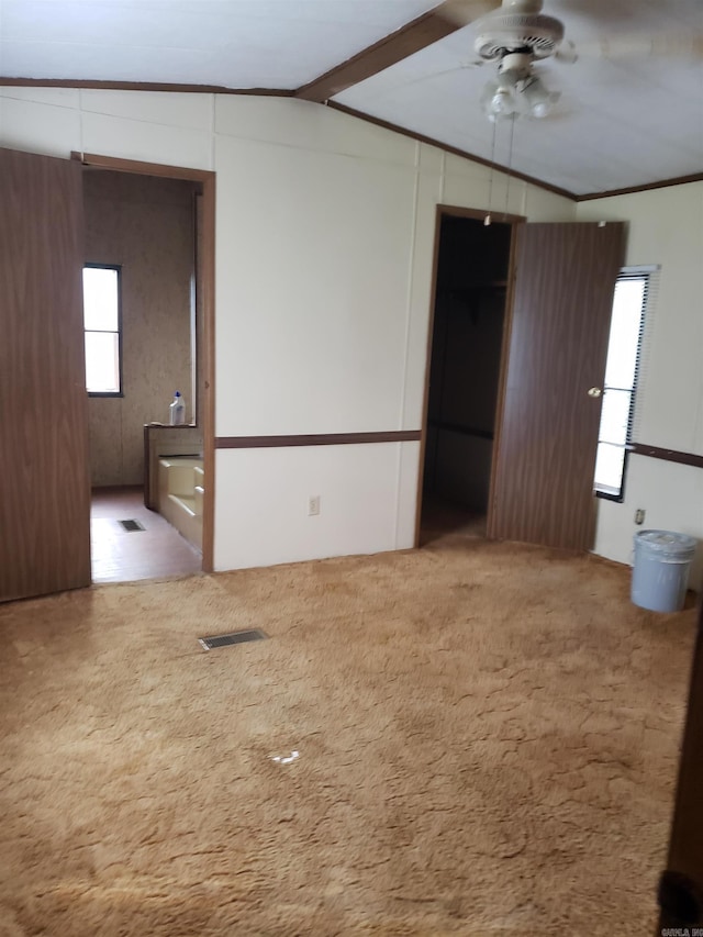 spare room featuring a ceiling fan, visible vents, lofted ceiling with beams, ornamental molding, and carpet flooring