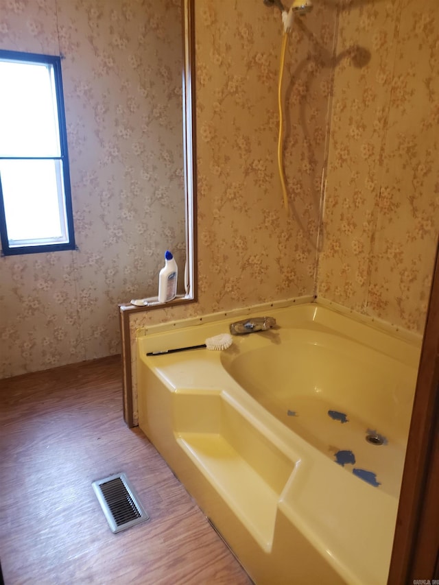 full bath with wallpapered walls, a bath, and visible vents