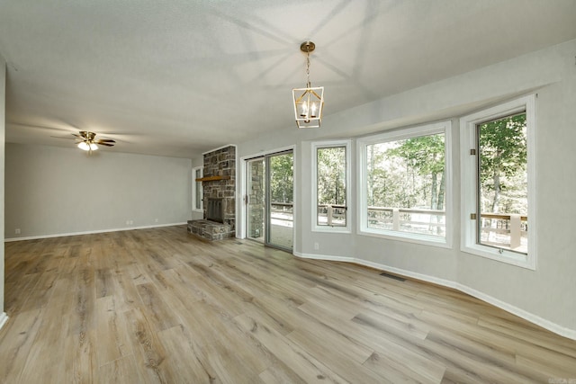 unfurnished living room featuring a wealth of natural light, visible vents, light wood-type flooring, and baseboards