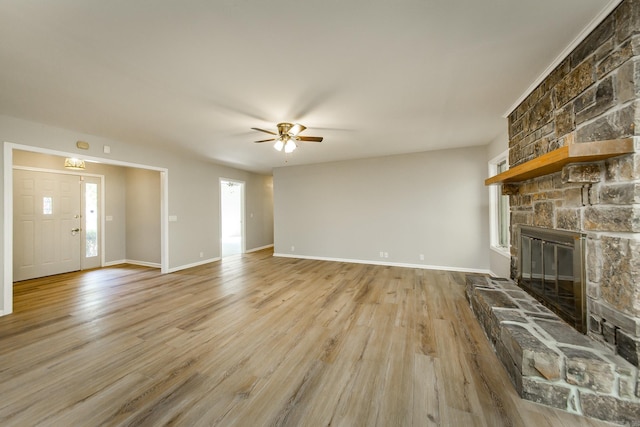 unfurnished living room with baseboards, a ceiling fan, wood finished floors, and a fireplace