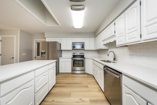 kitchen with a sink, white cabinetry, appliances with stainless steel finishes, and light wood finished floors