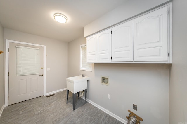 clothes washing area with visible vents, washer hookup, wood finished floors, cabinet space, and baseboards