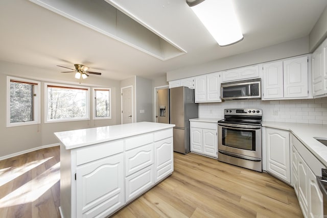 kitchen with light wood-type flooring, a kitchen island, tasteful backsplash, stainless steel appliances, and light countertops