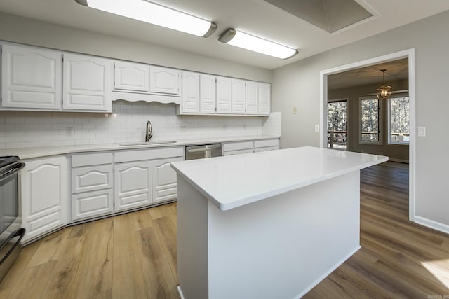 kitchen featuring a sink, white cabinetry, stainless steel appliances, light wood-style floors, and light countertops