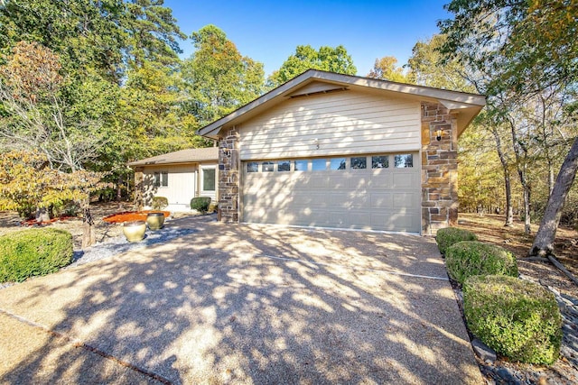 single story home featuring a garage, stone siding, and driveway