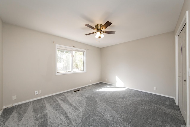 unfurnished room featuring visible vents, baseboards, ceiling fan, and dark carpet