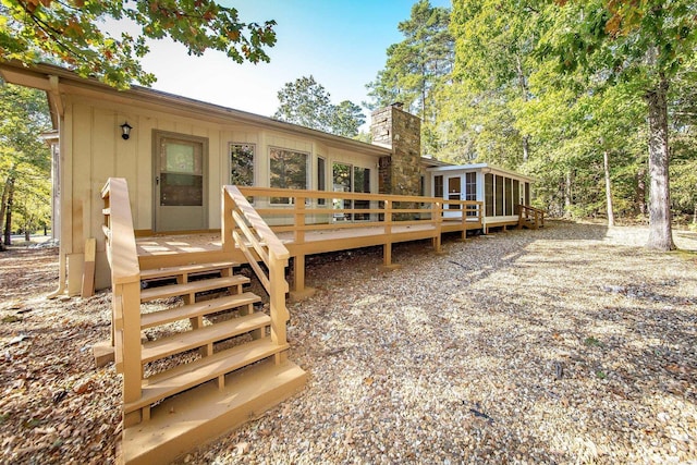 rear view of house featuring a deck, a chimney, and a sunroom