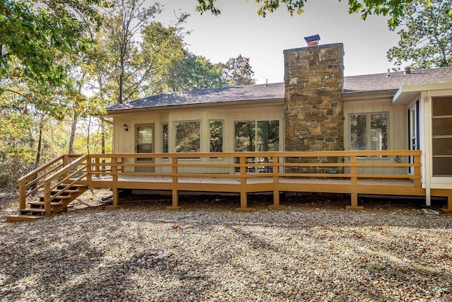 rear view of property with a wooden deck, a chimney, and roof with shingles