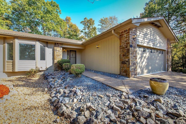 view of front facade featuring stone siding, driveway, and an attached garage