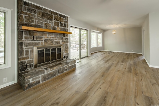 unfurnished living room with a fireplace, baseboards, and wood finished floors