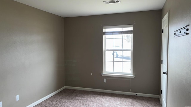 empty room with a wealth of natural light, visible vents, and carpet floors