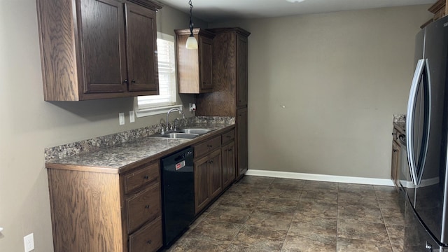 kitchen with dark countertops, baseboards, dishwasher, freestanding refrigerator, and a sink