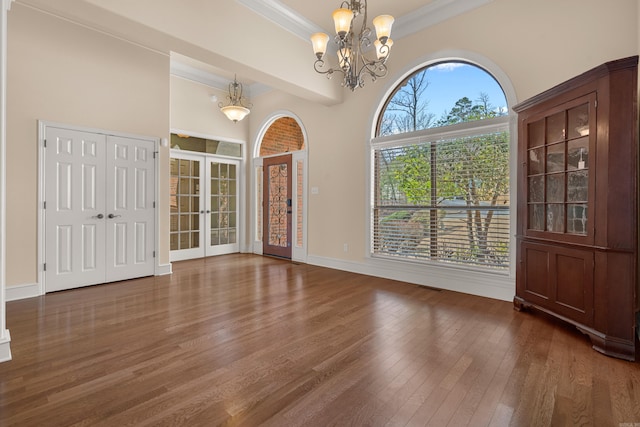 interior space with baseboards, ornamental molding, hardwood / wood-style floors, french doors, and an inviting chandelier