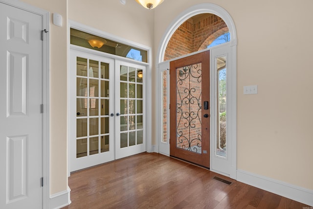 entrance foyer with wood finished floors, french doors, visible vents, and baseboards