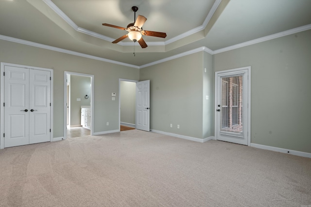 unfurnished bedroom with a raised ceiling, crown molding, baseboards, light colored carpet, and access to exterior