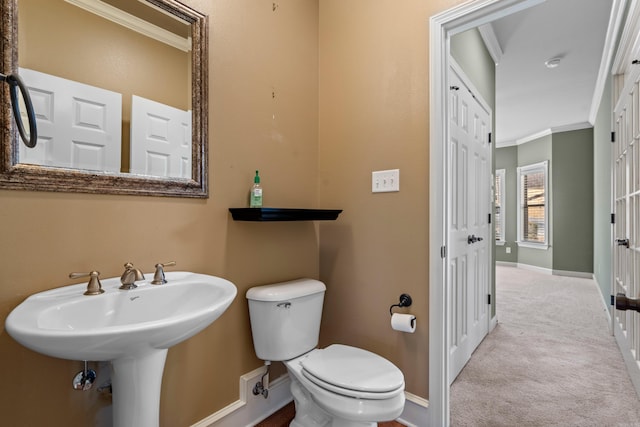 half bathroom with toilet, baseboards, and ornamental molding