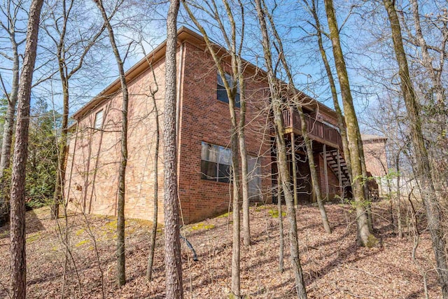 view of side of home with stairs, brick siding, and a wooden deck