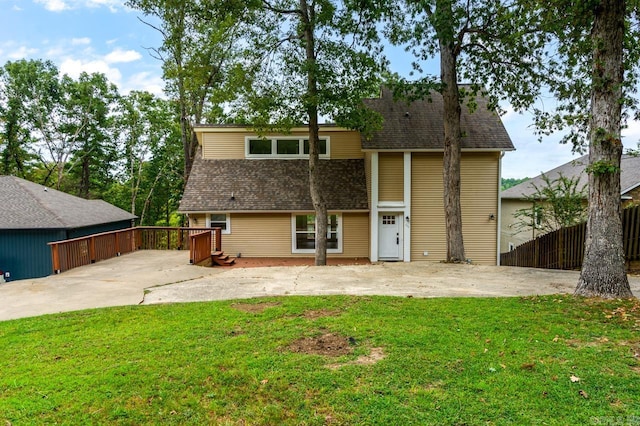 rear view of house featuring a patio area, a lawn, fence, and roof with shingles