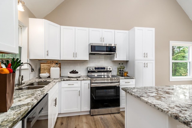 kitchen with light wood-style flooring, appliances with stainless steel finishes, white cabinets, and a sink
