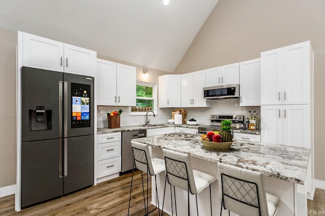 kitchen with a kitchen bar, white cabinets, a sink, and stainless steel appliances