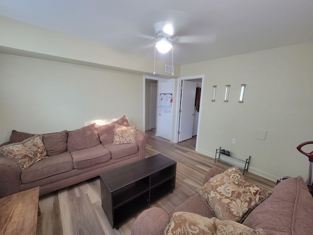 living room featuring visible vents, baseboards, and light wood finished floors