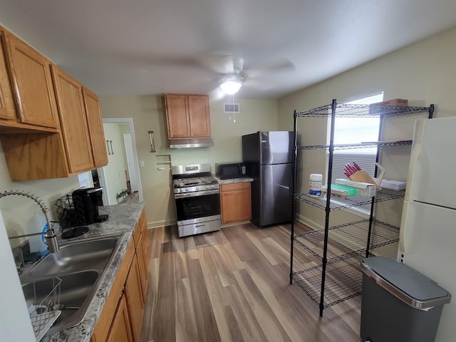 kitchen with light wood finished floors, visible vents, stainless steel appliances, a ceiling fan, and a sink