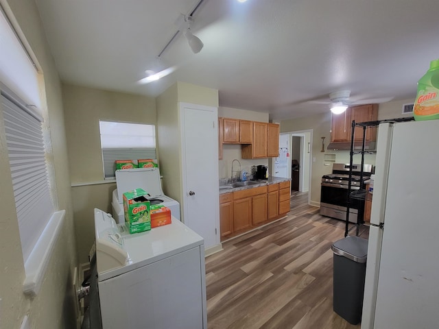 kitchen with stainless steel range with gas cooktop, freestanding refrigerator, wood finished floors, independent washer and dryer, and a sink