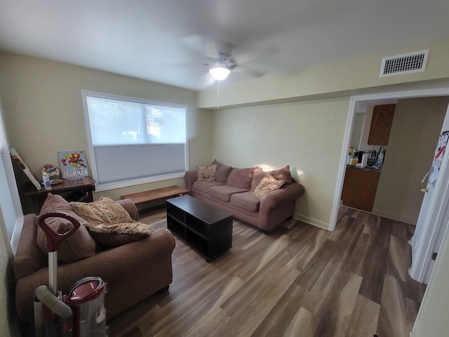 living room featuring visible vents, baseboards, a ceiling fan, and wood finished floors