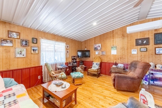 living room with lofted ceiling, wood finished floors, and a wall mounted AC