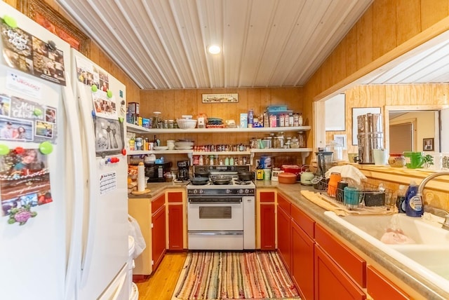 kitchen featuring a sink, light countertops, light wood-style flooring, white appliances, and open shelves