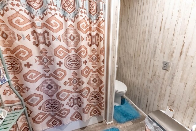 full bath featuring toilet, a shower with shower curtain, and wood finished floors